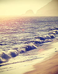 Vintage filtered beach at sunset with flare effect, California.