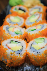 Sushi roll, row of California maki roll sushi with caviar on bla