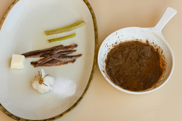 pan of bagna cauda with a dish of the ingredients that are used