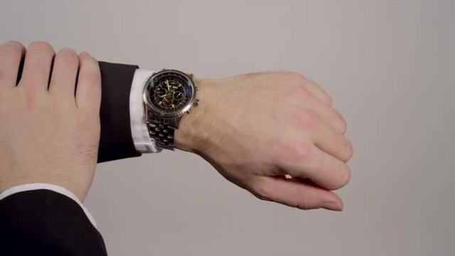 Businessman looks at his watch to check the time