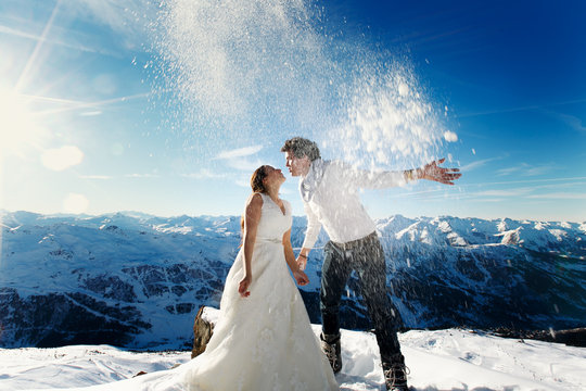 bride and groom in love throw snow on the background of the Alps