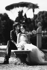 stylish charming rich bride and groom sitting on a bench in the