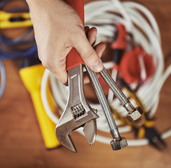Plumber hand holding instruments. Male builder ready to install faucet in a kitchen.  