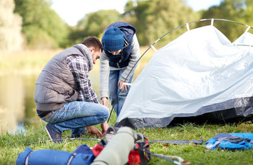 happy father and son setting up tent outdoors