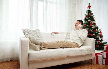 Obraz premium man calling on smartphone at home for christmas