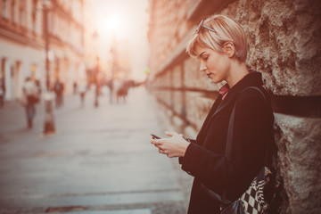 Portrait of beautiful young woman standing on the street and using her mobile phone