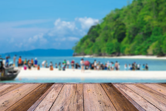 Empty wooden table and blurred Crowds of visitors enjoy a day trip at talay waek krabi, thailand