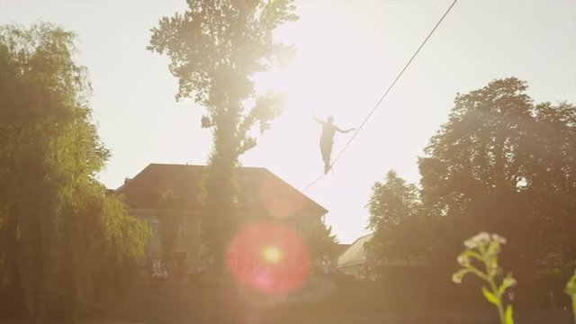 Man walking on high slackline above the street in city