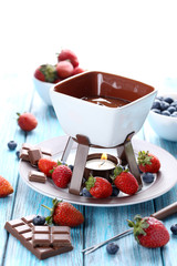 Chocolate fondue with fresh berries on a blue wooden table