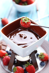 Chocolate fondue with fresh berries on a blue wooden table