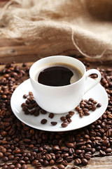 Cup of coffee with coffee beans on a brown wooden background
