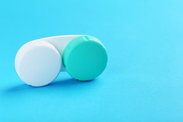 Contact lenses in container with solution on blue background