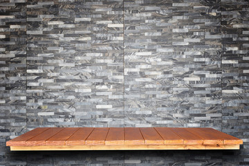 Empty top wooden shelves and stone wall background