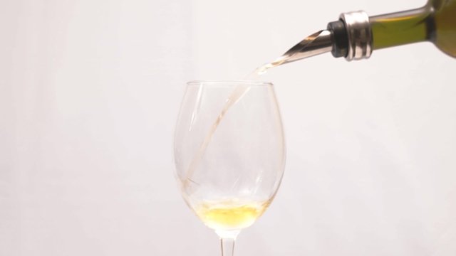 vino bianco, vino Moscato viene versato in un bicchiere su uno sfondo bianco