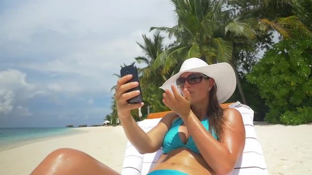 Young woman taking selfies on an exotic beach in Maldives