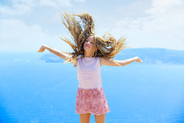 Naklejka premium Blond girl shaking hair on air at blue Mediterranean