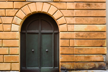 Yellow wall with medieval door in the Tuscan town Siena Italy