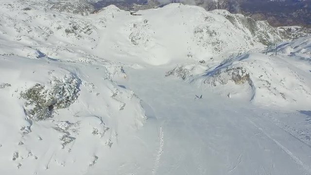 AERIAL: Snowboarder riding down the ski slope