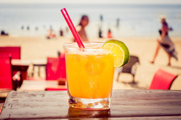 Delicious refreshing yellow cocktail with beach in the background