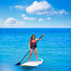 Kid paddle surf surfer girl with row in the beach