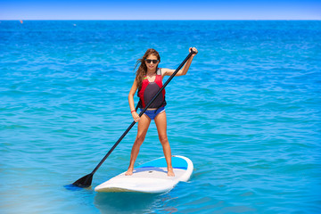 Fototapeta premium Kid paddle surf surfer girl with row in the beach