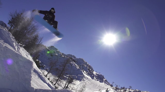 SLOW MOTION: Snowboarder jumping over the sun