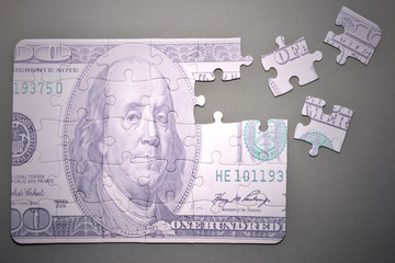 puzzle with the one hundred dollars banknote on a gray background