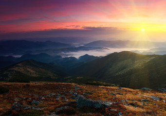 Colorful sunrise in the mountains. Fog in the valley.