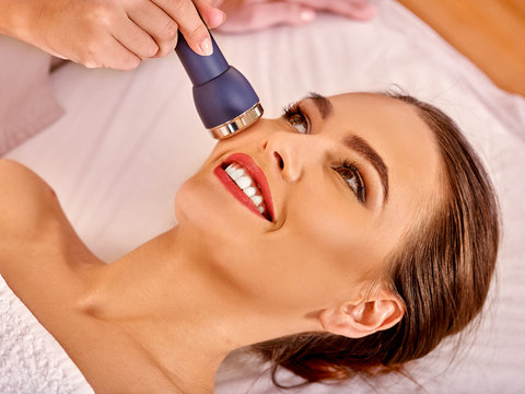 Young woman receiving electric facial massage.