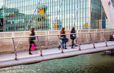 LONDON, UK - May 18, 2015:  People walking through the bridge in Canary Wharf business 