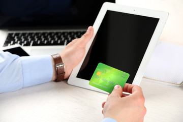 Man holding credit card and tablet on workplace background