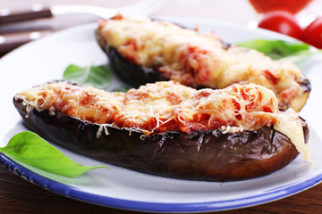 Dish of eggplant with cherry tomatoes and cheese in white plate on wooden table, closeup