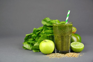 Green healthy juice with fruits and herbs on gray background