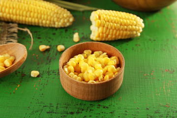 Fresh corn on cobs on green wooden background