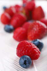 Tasty ripe berries on plate close up