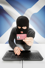 Hacker with flag on background holding ID card in hand - Scotland