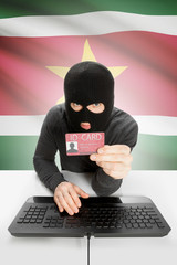 Hacker with flag on background holding ID card in hand - Suriname