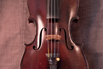 Antique violin against gray fabric background