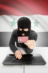 Hacker with flag on background holding ID card in hand - Syria