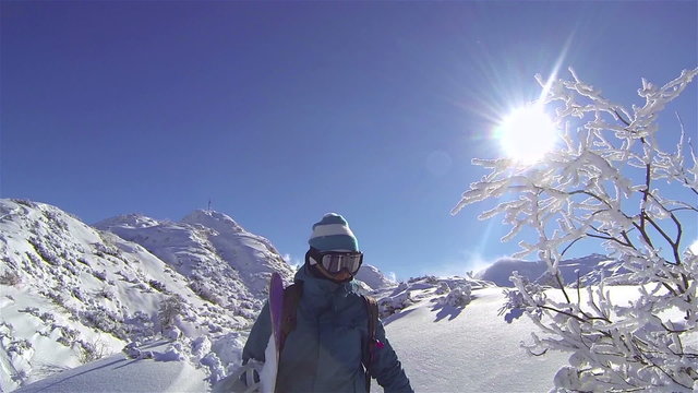 SLOW MOTION: Female snowboarder hiking in mountains