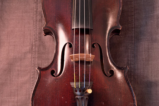 Antique violin against gray fabric background
