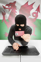 Hacker with flag on background holding ID card in hand - Wales