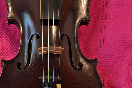 Antique violin closeup against pink fabric