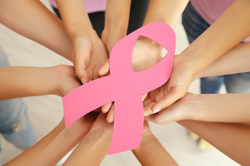 Women hands joined in circle holding breast cancer symbol