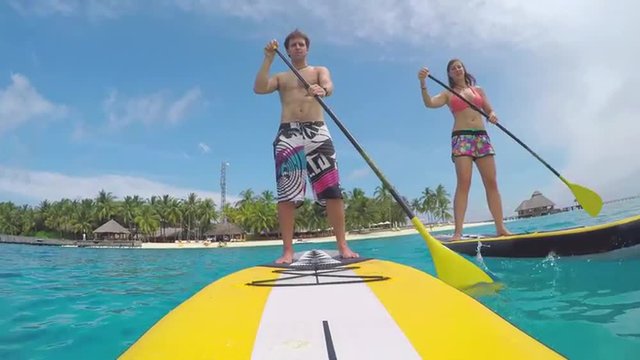 Young couple SUP boarding in exotic maldives