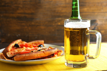 Sliced pizza served with beer on wooden table