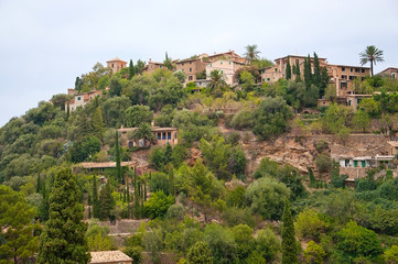 Obraz premium Lush hills near Deia with traditional drystone buildings on an overcast day in July in Mallorca, Balearic islands, Spain.