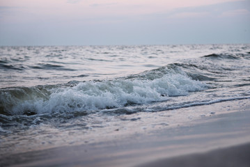 Naklejka na ściany i meble Sea wave on the shore at sunset