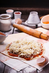 pizza preparation surrounded by ingredients