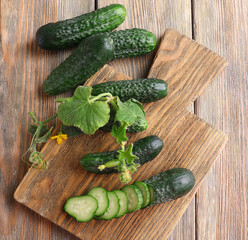 Sliced cucumbers and kitchen board on wooden background